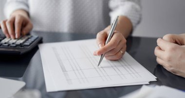 Müşteri için vergi sayarken hesap makinesi ve dizüstü bilgisayar kullanan kadın muhasebeci. İş denetimi ve finans kavramları.