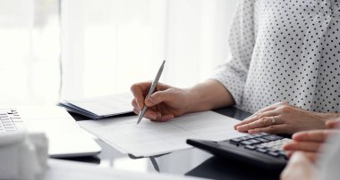 Müşteri ile vergileri sayıp tartışırken hesap makinesi ve dizüstü bilgisayar kullanan kadın muhasebeci. İş denetimi ve finans kavramları.