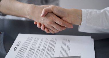 Ofisteki cam masada otururken sözleşmeyi imzalayan işadamları, yakın plan. Toplantıda ortaklar ya da avukatlar birlikte çalışıyor. Takım çalışması, ortaklık, başarı kavramı.