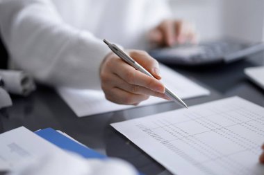 Müşteri için vergi sayarken hesap makinesi ve dizüstü bilgisayar kullanan kadın muhasebeci. İş denetimi kavramları.