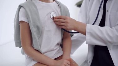 Doktor ve hasta. Doktor, klinikteki olağan tıbbi muayenede steteskoplu bir kızı muayene ediyor. Tıp konsepti.