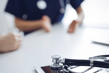 Steteskop arka planda bir doktor ve hastanın önünde tablet bilgisayarın üzerinde duruyordu. Tıp, sağlık hizmeti kavramı.