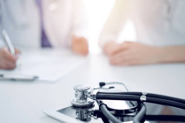 Stetoskop arka planda yan yana oturan bir doktor ve hastanın önündeki tabletin üzerinde duruyordu. Tıp, sağlık hizmeti kavramı.