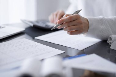 Müşteri için vergi sayarken hesap makinesi ve dizüstü bilgisayar kullanan kadın muhasebeci. İş denetimi kavramları.