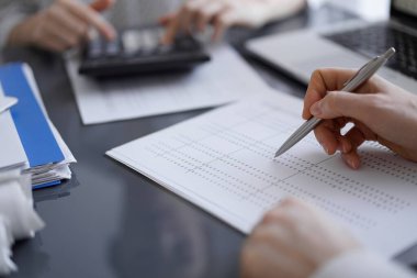 Müşteri için vergi sayarken hesap makinesi ve dizüstü bilgisayar kullanan kadın muhasebeci. İş denetimi kavramları.