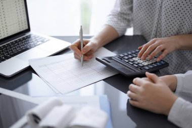 Müşteri için vergi sayarken hesap makinesi ve dizüstü bilgisayar kullanan kadın muhasebeci. İş denetimi kavramları.