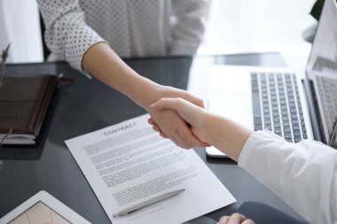 İş adamları anlaşma kağıtlarının üzerinde el sıkışıyorlar. Beyaz masaya yeni imzalanmış, yakın plan. Toplantıdaki avukatlar. Takım çalışması, ortaklık, başarı kavramı.