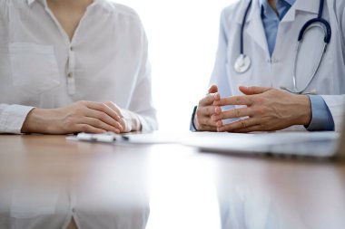 Doktor ve hasta, klinikteki ahşap masada yan yana otururken bir şey tartışıyorlar. Tıp konsepti.