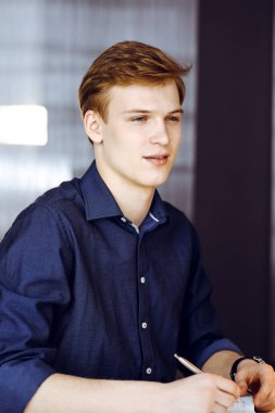 Bilgisayarla çalışan genç sarışın iş adamı. Girişim işi, başarı için çok çalışmak ve zamanın dışında çalışmak demektir..