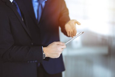 İş adamları güneşli ve modern bir ofiste çalışırken tablet bilgisayar kullanıyorlar. İş yerinde iş arkadaşı olan tanınmamış bir iş adamı ya da erkek girişimci. Takım çalışması ve ortaklık kavramı.