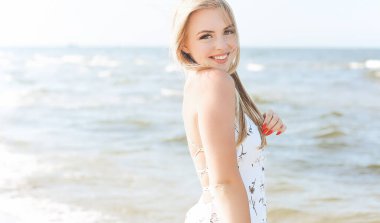 Mutlu sarışın kadın okyanus sahilinde mutlu mesut durup poz veriyor..