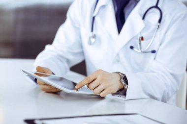 Bilinmeyen erkek doktor klinikteki tablet bilgisayarla yakın planda çalışıyor. İşteki genç doktor. Mükemmel sağlık hizmeti, tıp konsepti.