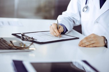 Bilinmeyen erkek doktor, klinikteki ilaç geçmişi kayıtlarıyla birlikte yakın planda oturuyor. İşteki genç doktor. Mükemmel sağlık hizmeti, tıp konsepti.