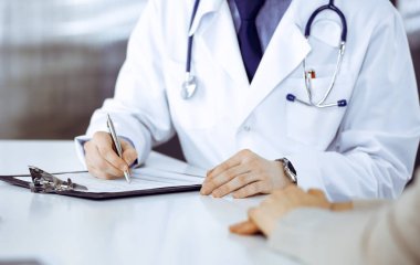 Bilinmeyen erkek doktor ve hasta kadın klinikte oturup dosya kullanırken bir şey tartışıyorlar. Hastanedeki en iyi sağlık hizmeti, ilaç, salgın durdurma..
