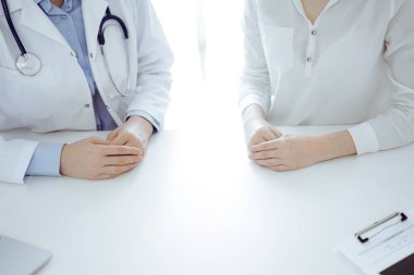 Doktor ve hasta klinikteki masada yan yana oturuyorlar, yakın plan. Tıp konsepti.