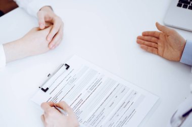 Doktor ve hasta birbirlerine karşı otururken sağlık sorularını tartışıyorlar ve klinikteki masada pano kullanıyorlar, sadece elleri yakın çekim. Tıp konsepti.