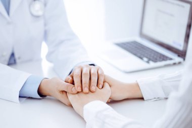 Doktor ve hasta klinikteki masada karşılıklı oturuyorlar. Kadın doktorlara odaklan. Kadına güven veren eller, sadece eller, yakın çekim. Tıp konsepti.