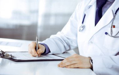 Bilinmeyen erkek doktor, klinikteki ilaç geçmişi kayıtlarıyla birlikte yakın planda oturuyor. İşteki genç doktor. Mükemmel sağlık hizmeti, tıp konsepti.