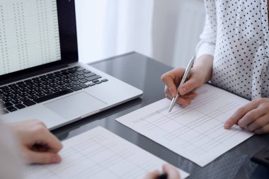 İki muhasebeci vergi veya gelir dengesi saymak için bir hesap makinesi ve dizüstü bilgisayar kullanıyor. İş, denetim ve vergi kavramları.