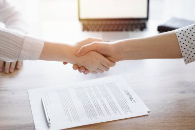 İş adamları kontrat kağıtlarının üzerinde el sıkışıyor. Tahta masaya yeni imzalanmış. Kapatın. Toplantıdaki avukatlar. Takım çalışması, ortaklık, başarı kavramı.