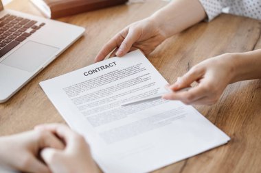 İş kadını avukat, ofisteki ahşap masada meslektaşı ya da müvekkili için bir şey itiraf eden özel sözleşmeye işaret ediyor. İş adamları takım çalışması ve ortaklık, toplantı konsepti.