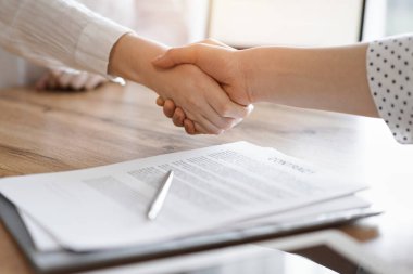 İş adamları kontrat kağıtlarının üzerinde el sıkışıyor. Tahta masaya yeni imzalanmış. Kapatın. Toplantıdaki avukatlar. Takım çalışması, ortaklık, başarı kavramı.