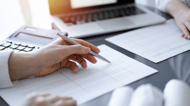 Müşteri için vergi sayarken hesap makinesi ve dizüstü bilgisayar kullanan kadın muhasebeci. İş denetimi kavramları.