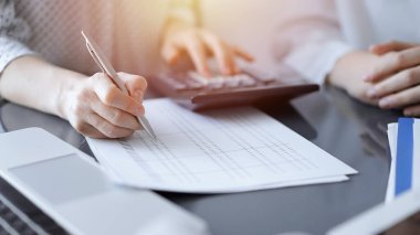 Müşteri için vergi sayarken hesap makinesi ve dizüstü bilgisayar kullanan kadın muhasebeci. İş denetimi kavramları.