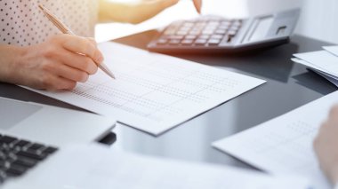 Müşteri için vergi sayarken hesap makinesi ve dizüstü bilgisayar kullanan kadın muhasebeci. İş denetimi kavramları.