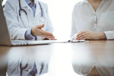 Doktor ve hasta, klinikteki ahşap masada yan yana otururken bir şey tartışıyorlar. Tıp konsepti.