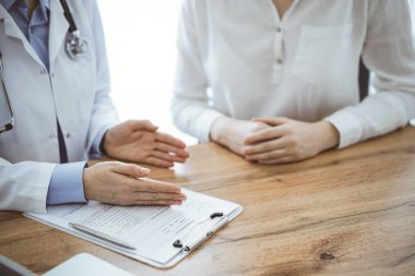 Doktor ve hasta, yukarıdan bakıldığında, klinikteki ahşap masada yan yana otururken bir şeyler tartışıyorlar. Tıp konsepti.