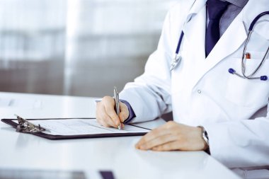 Bilinmeyen erkek doktor, klinikteki ilaç geçmişi kayıtlarıyla birlikte yakın planda oturuyor. İşteki genç doktor. Mükemmel sağlık hizmeti, tıp konsepti.