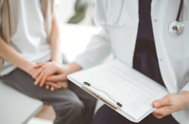 Doktor ve çocuk hasta. Hekim elinde bir dosya tutuyor ve bir çocuğu rahatlatıyor. Tıptaki ideal sağlık kavramı.