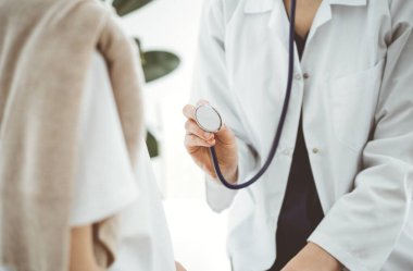 Doktor ve bir çocuk hasta. Doktor steteskop tutuyor ve çocuğu muayene etmeye hazır. Tıpta mükemmel sağlık kavramı.
