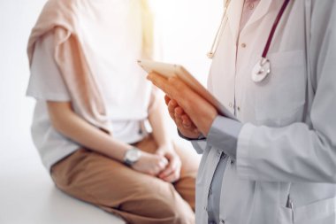 Doctor and patient discussing perfect health exam results. Friendly physician keeping tablet computer with her hands near a young woman. Medicine concept. clipart