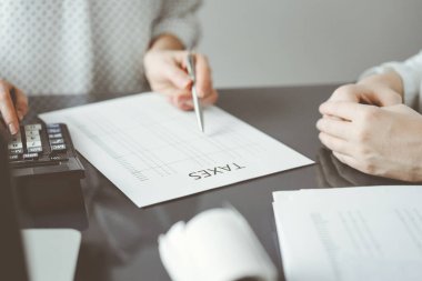 Müşteri için vergi sayarken hesap makinesi ve dizüstü bilgisayar kullanan kadın muhasebeci. İş denetimi ve finans kavramları.