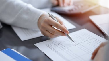 Müşteri için vergi sayarken hesap makinesi ve dizüstü bilgisayar kullanan kadın muhasebeci. İş denetimi kavramları.