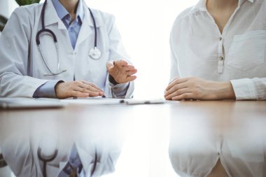 Doktor ve hasta, klinikteki ahşap masada yan yana otururken bir şey tartışıyorlar. Tıp konsepti.
