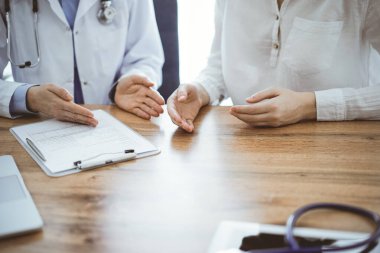 Doktor ve hasta, yukarıdan bakıldığında, klinikteki ahşap masada yan yana otururken bir şeyler tartışıyorlar. Tıp konsepti.