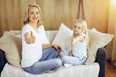 Güneşli dairede mutlu bir aile. Sarışın genç anne sevimli kızıyla oynuyor ve sarılıyor. Annelik kavramı.