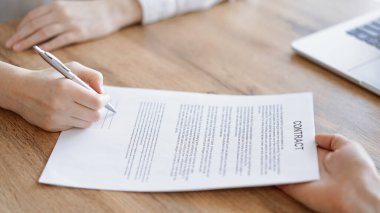 Ofisteki ahşap masada otururken sözleşmeyi imzalayan işadamları, yakın plan. Toplantıda ortaklar ya da avukatlar birlikte çalışıyor. Takım çalışması, ortaklık, başarı kavramı.