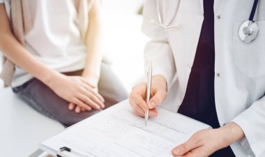 Doktor ve çocuk hasta. Hekim bir çocuğun yanında pano tutuyor ve tıbbi kayıt formunda yazıyor. Tıptaki ideal sağlık kavramı.