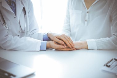 Doktor ve hasta klinikteki masada yan yana oturuyorlar. Kadın doktorlara odaklan. Kadına güven veren eller, sadece eller, yakın çekim. Tıp konsepti.