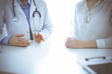 Doktor ve hasta klinikteki masada yan yana otururken sağlık sorunlarını tartışıyorlar. Sadece ellerinizi yakın tutun. Tıp konsepti.