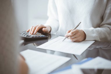 Müşteri için vergi sayarken hesap makinesi ve dizüstü bilgisayar kullanan kadın muhasebeci. İş denetimi kavramları.