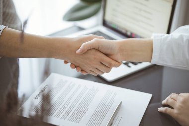İş adamları kontrat kağıtlarının üzerinde el sıkışıyorlar. Ahşap masaya yeni imzalanmış, yakın plan. Toplantıdaki avukatlar. Takım çalışması, ortaklık, başarı kavramı.
