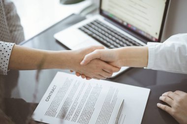 İş adamları kontrat kağıtlarının üzerinde el sıkışıyorlar. Ahşap masaya yeni imzalanmış, yakın plan. Toplantıdaki avukatlar. Takım çalışması, ortaklık, başarı kavramı.