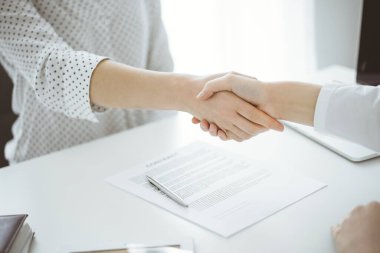 İş adamları anlaşma kağıtlarının üzerinde el sıkışıyorlar. Beyaz masaya yeni imzalanmış, yakın plan. Toplantıdaki avukatlar. Takım çalışması, ortaklık, başarı kavramı.