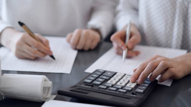 İki muhasebeci vergi veya gelir dengesi saymak için bir hesap makinesi ve dizüstü bilgisayar kullanıyor. İş, denetim ve vergi kavramları.