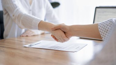 İş adamları kontrat kağıtlarının üzerinde el sıkışıyor. Tahta masaya yeni imzalanmış. Kapatın. Toplantıdaki avukatlar. Takım çalışması, ortaklık, başarı kavramı.